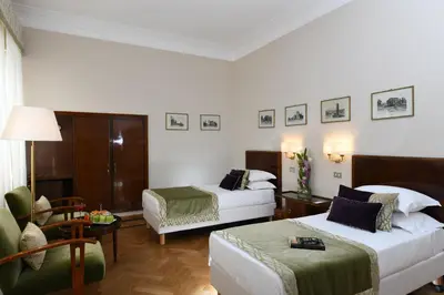 a hotel room with two beds and a couch at Bettoja Hotel Atlantico in Rome