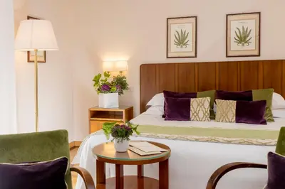 a hotel room with a bed and a table with chairs at Bettoja Hotel Atlantico in Rome