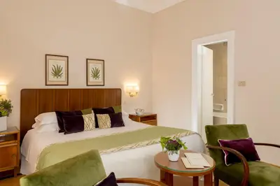 a bedroom with a bed and a table and chairs at Bettoja Hotel Atlantico in Rome
