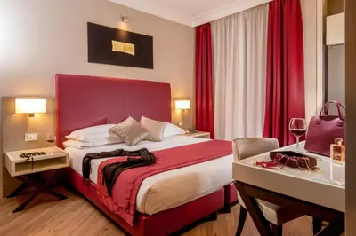 a hotel room with a large bed and red curtains at Ludovisi Palace Hotel in Rome