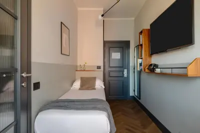 a small bedroom with a bed and a flat screen tv at c-hotels Club House Roma in Rome