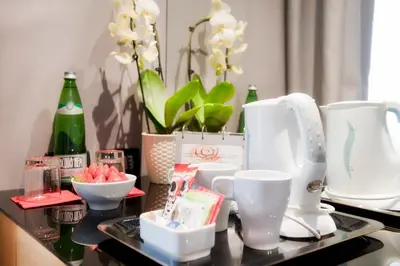 a tray with cups and bottles on a table with flowers at Best Western Ars Hotel in Rome