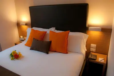 a bed with orange and white pillows and a flower on it at Hotel Concordia in Rome