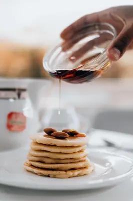 a person is pouring syrup onto a stack of pancakes at Hotel Pantheon in Rome