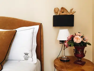 a bed with a vase of flowers on a table with a lamp at Casa Roma Luxury Apartment in Rome