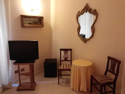 a living room with a tv and chairs and a mirror at Marta Guest House in Rome