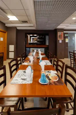 a long wooden table in a room with chairs at Scheppers Hotel in Rome