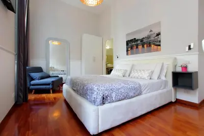 a white bedroom with a white bed and a chair at 4BNB - Otranto Vatican Apartment in Rome
