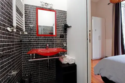 a bathroom with a red sink and black tiles at 4BNB - Otranto Vatican Apartment in Rome