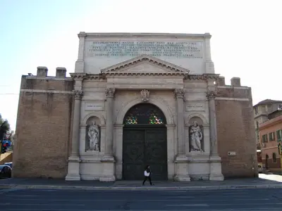 a woman walking in front of a building with a large door at Baltik Guesthouse in Rome