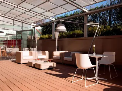 a patio with white furniture on a wooden deck at Hotel Zone in Rome