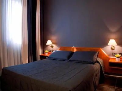 a bedroom with a blue bed with two lamps on two tables at Hotel Zone in Rome