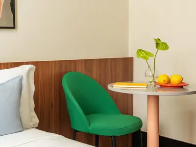 a table with a green chair and a table with fruit on it at Numa Rome Barberini in Rome