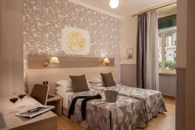 a hotel room with two beds and a desk with a laptop at Hotel Dorica in Rome