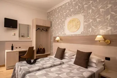 a hotel room with two beds and a desk at Hotel Dorica in Rome