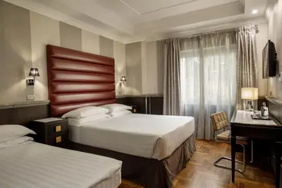 a hotel room with two beds and a desk at Hotel Royal Court in Rome