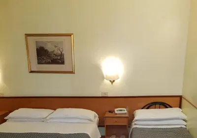 a hotel room with two beds and a phone on the wall at Hotel Piemonte in Rome