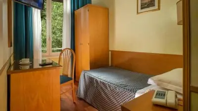 a bedroom with a bed and a desk with a telephone at Hotel Piemonte in Rome