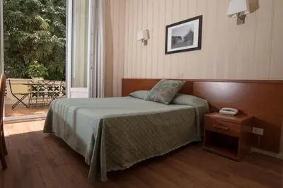 a bedroom with a bed and a table and a window at Hotel Villa Delle Rose in Rome