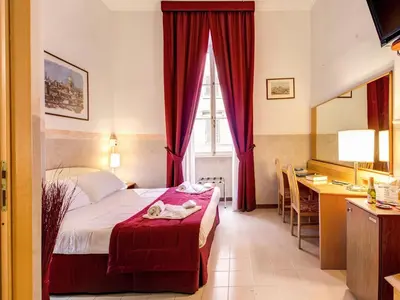 a bedroom with a bed with red curtains and a desk at Hotel Giotto Flavia in Rome