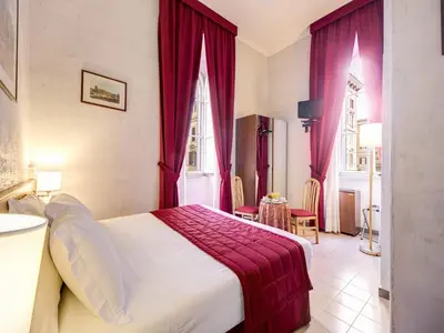 a bedroom with a large bed with red curtains at Hotel Giotto Flavia in Rome