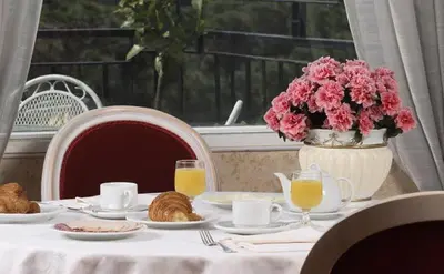 a table with plates of food and a vase of pink flowers at Hotel Eliseo in Rome