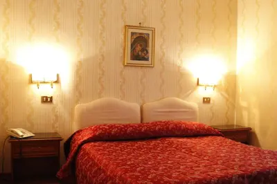 a bedroom with a bed with a red blanket and two lamps at Hotel Torino in Rome