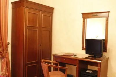 a room with a desk with a television and a cabinet at Hotel Torino in Rome