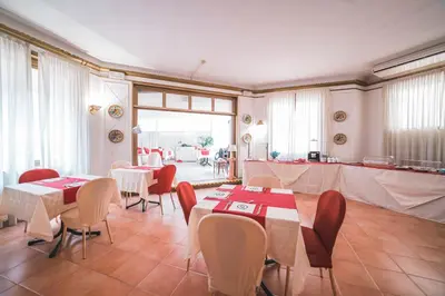 a dining room with tables and chairs and a kitchen at GH Hotel San Giusto in Rome