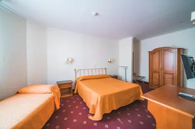 a hotel room with two beds and a desk at GH Hotel San Giusto in Rome