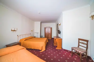 a hotel room with two beds and a chair at GH Hotel San Giusto in Rome
