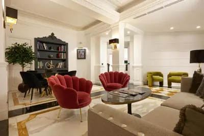 a living room with red chairs and a piano at Hotel Barberini in Rome