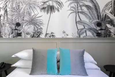 a bed with two pillows and a mural of palm trees at Hotel Coppede' in Rome