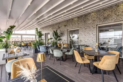 a restaurant with tables and chairs and plants at La Griffe Hotel Roma in Rome