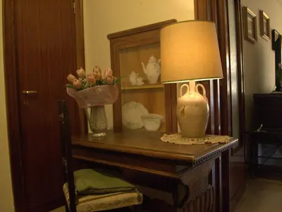 a table with a lamp and a vase with flowers on it at B&B All'Ombra di San Pietro in Rome