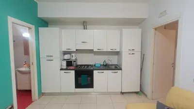 a kitchen with white cabinets and a stove top oven at Olimpo Apartments St John in Lateran in Rome