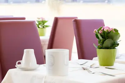 a table with a cup and a vase of flowers on it at Romoli Hotel in Rome