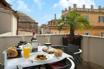 a table with food and glasses of wine on a balcony at Antico Albergo del Sole al Pantheon in Rome