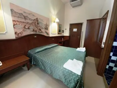 a bedroom with a green bed and a painting on the wall at Cambridge Hotel in Rome