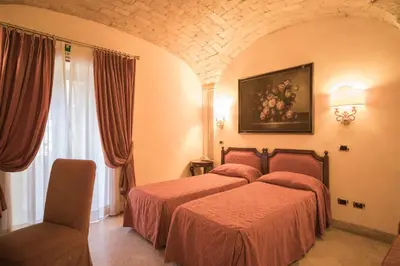 a hotel room with two beds and a window at Hotel Donatello in Rome