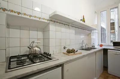 a white tiled kitchen with a stove and sink at Colosseo et Esquilino - LOCAPPART in Rome