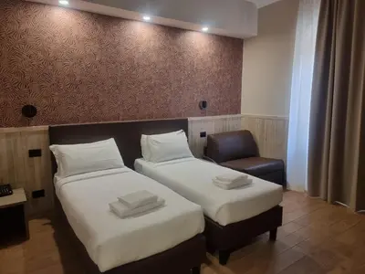a hotel room with two beds and a chair at Hotel Pyramid in Rome