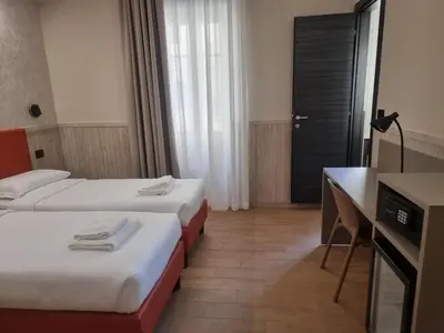 a hotel room with two beds and a desk and a desk at Hotel Pyramid in Rome