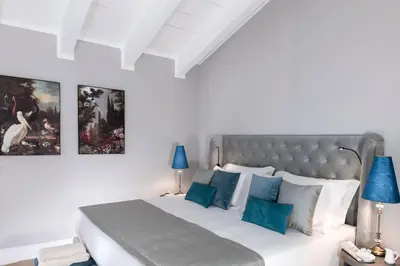a white bedroom with a large bed with blue pillows at Hotel La Ville Rome in Rome