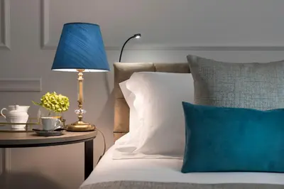 a bed with a blue lamp on a table with a blue pillow at Hotel La Ville Rome in Rome