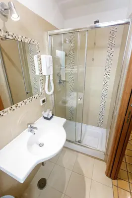 a white bathroom with a shower and a sink at Hotel Lirico in Rome