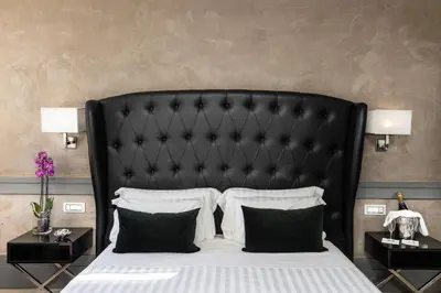a bedroom with a large black bed with pillows at Hotel Castellino Roma in Rome