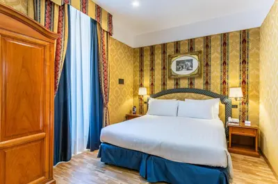 a hotel room with a bed and a cabinet at Hotel Raffaello - Sure Hotel Collection by Best Western in Rome