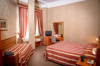 a hotel room with two beds and a desk at Hotel Emmaus in Rome