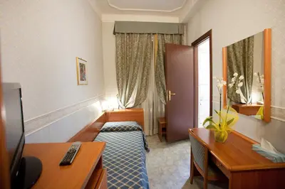 a hotel room with two beds and a desk at Hotel Emmaus in Rome